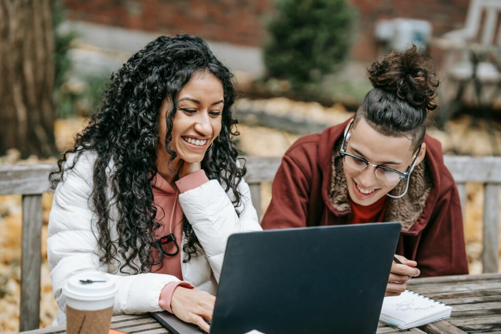 Young diverse positive students surfing internet on laptop